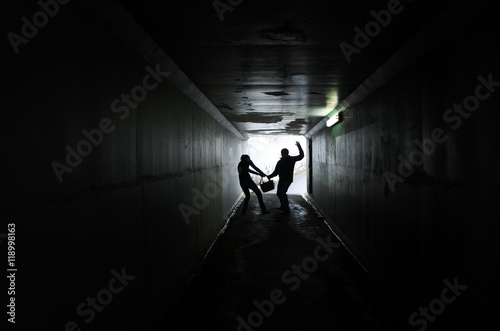 Man thief steals a bag from a woman in a dark tunnel