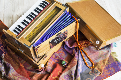 Indian harmonium, a traditional wooden keyboard instrument, close-up. Bright colorful musical instrument on the patterned wrap