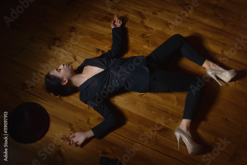 Woman in a black suit with gun lying on the floor