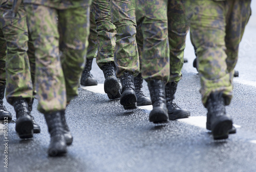 Soldiers marching on the asphalt road. Image of black boots and camouflage clothes.