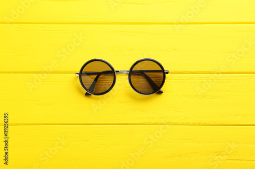 Black sunglasses on a yellow wooden table