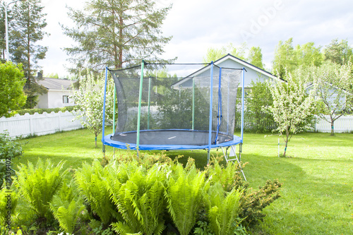 Blue trampoline on the lawn in garden