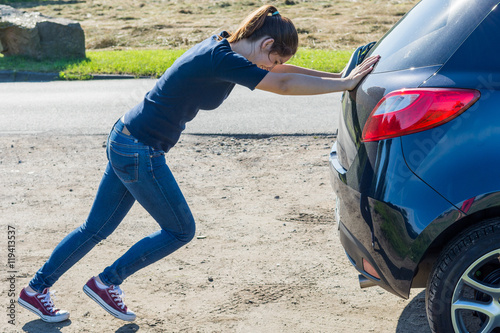 junge frau schiebt ein auto an