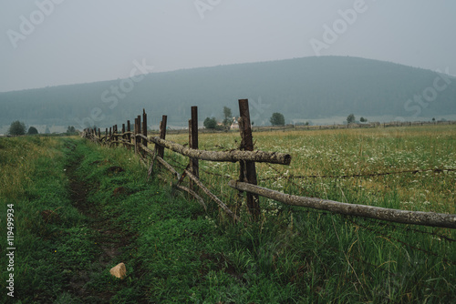 Old fence for cattle on a cloudy summer day