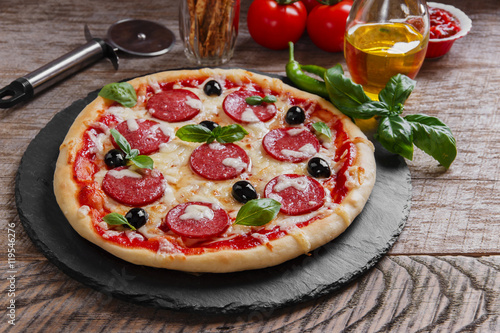 pizza with salami tomato and cheese on a wooden surface