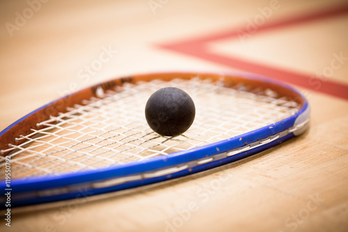 Close up of a squash ball on racket over wooden background