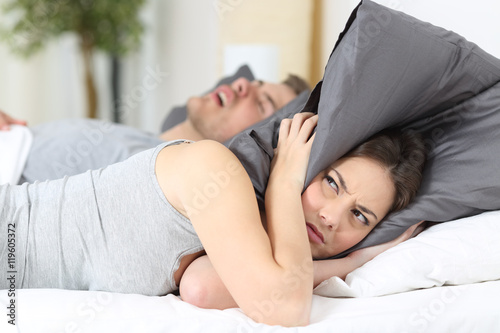 Man snoring and his wife covering ears