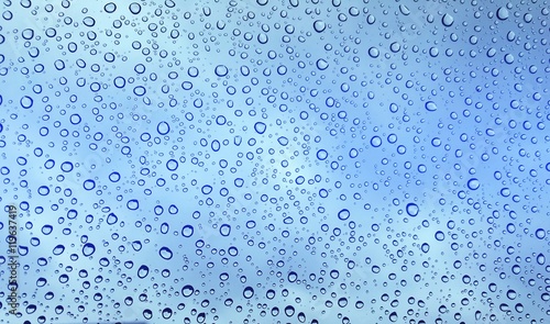 Rain drops on glass window blue gradient background