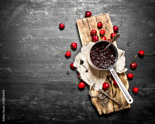 Fresh cherry jam in a saucepan on old Board.