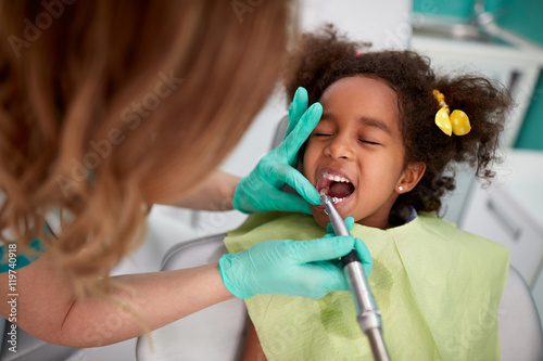 Female dentist patiently polish teeth to child .
