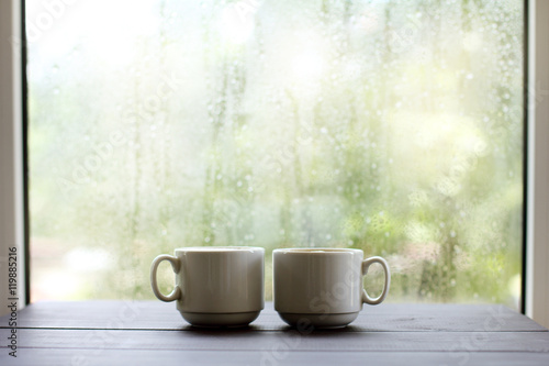cozy atmosphere for coffee breaks/ Two the light cup of coffee on a wooden table, against the window after rainy weather 