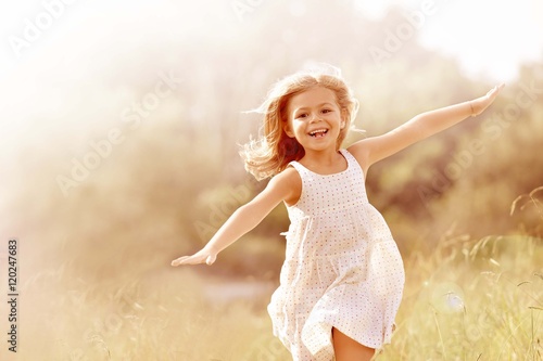 Little girl running in country field in summer