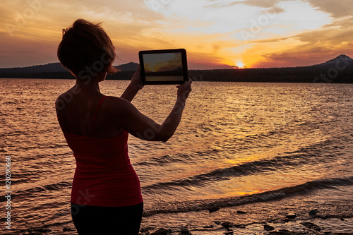 Girl photographing the sunset on the table