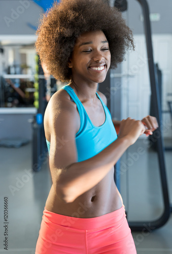 Young african female in a gym in front of gym equipment