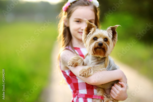 Cute little girl holding her yorkshire terrier dog