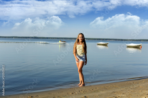 Piękna dziewczynka spaceruje brzegiem jeziora.
