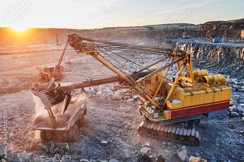 Mining. excavator loading granite or ore into dump truck