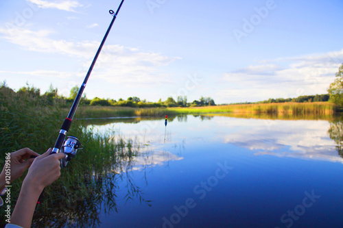 Fishing rod in hand on a background of lake