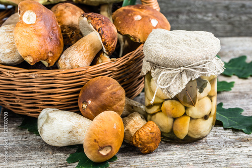 Boletus mushrooms marinated in jar on rustic wooden table, autum