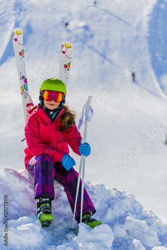  Portrait of happy young girl sitting in the snow with ski in wi