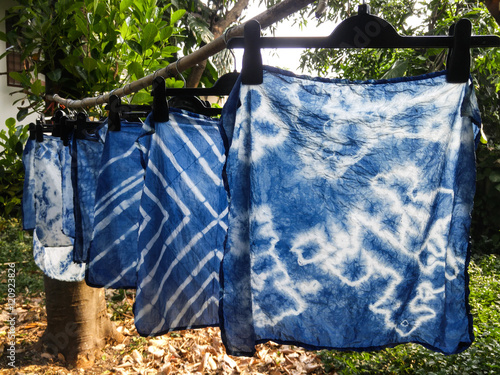 Beautiful natural indigo tie dye fabric with garden view in background.