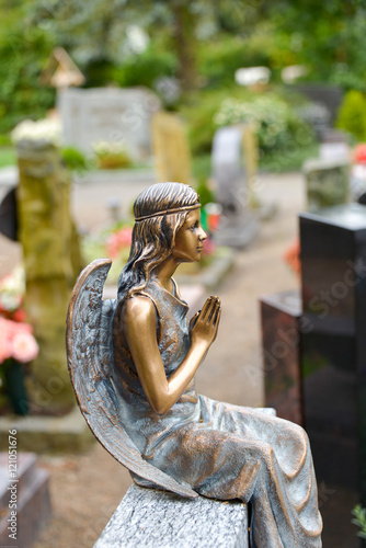 Betender Engel sitzt auf dem Grabstein
