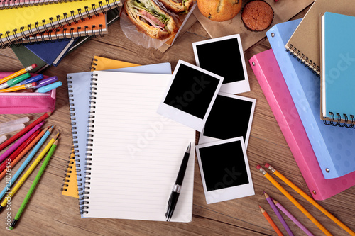 Several four polaroid style photo print frame on a college student or school desk with photo album notebook or scrapbook and education accessories