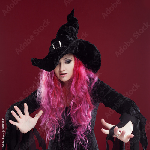 Attractive woman in witches hat and costume with red hair. Halloween