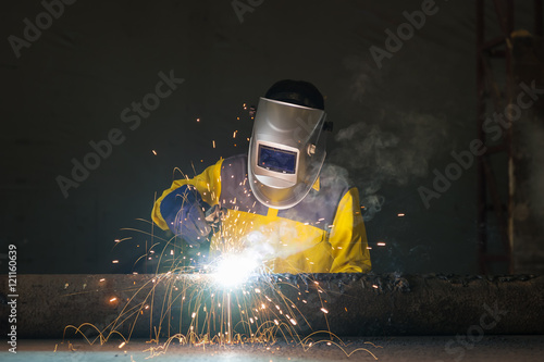 Industrial welder in manufacturing plant welding to finish a pipeline