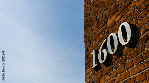 Building with address sign saying 1600 against blue sky on a sunny day