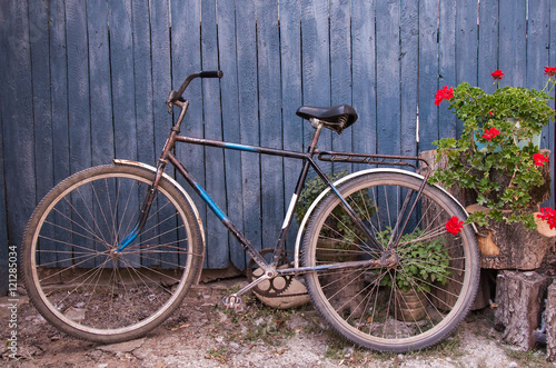 Old bicycle near a blue wooden fence in village