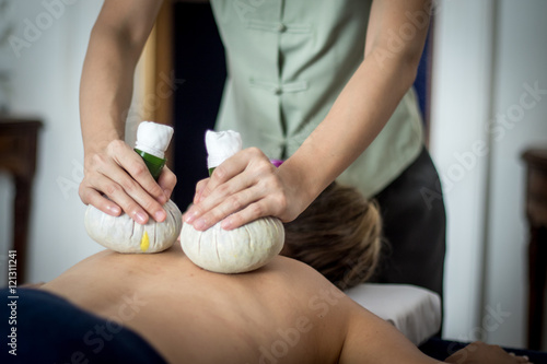 woman getting thai herbal compress massage in spa 