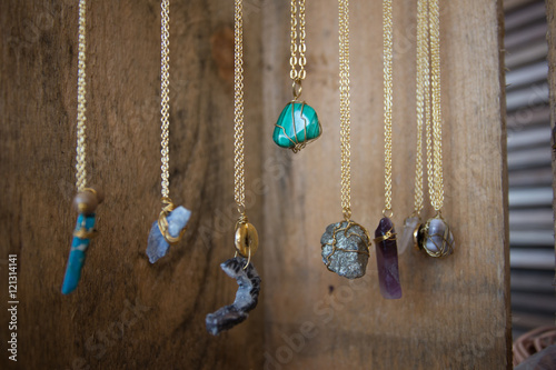Handmade Jewelry Hanging in front of Wooden Boards