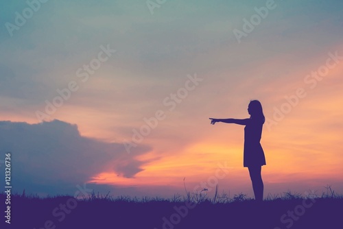 ilhouette young woman pointing forward to Dream ahead in sunset