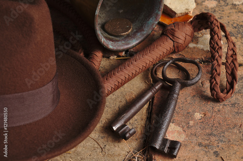 Fedora hat, bullwhip and relics on an antique tiled floor. Indiana theme