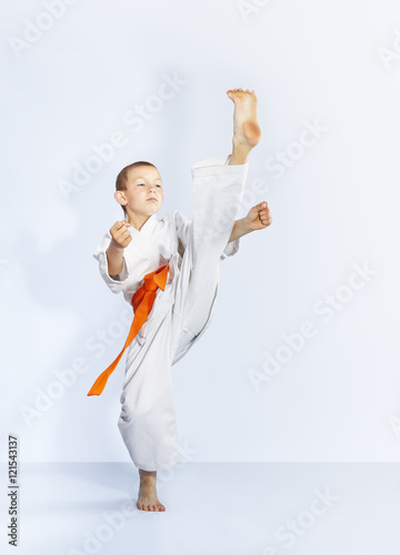 Karateka with an orange belt is beating kick leg