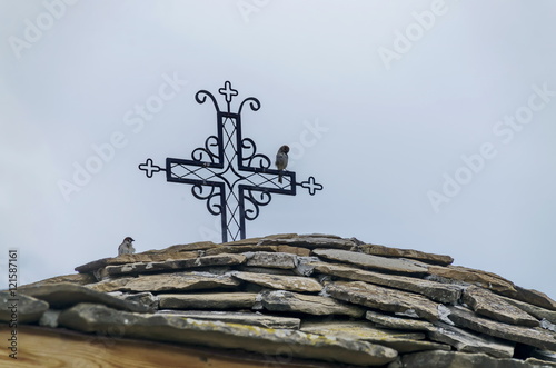 Stone slate-roof of old medieval church with cross in restored Montenegrin or Giginski monastery St. St. Cosmas and Damian, mountain Kitka, Breznik, Pernik region, Bulgaria 