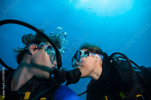 Scuba divers kissing each other underwater