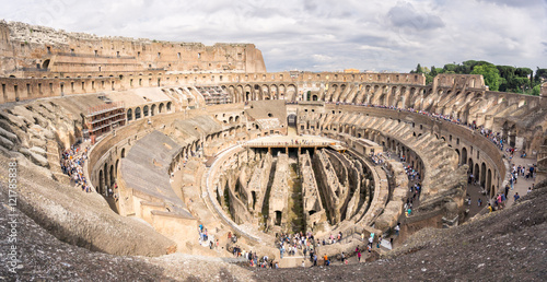 A wide view of the inside of the Coliseum in Rome from the uppermost levels, with unrecognisable tourists on the lower levels.
