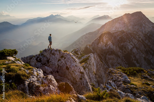 Man standing on a mountain summit at sunset