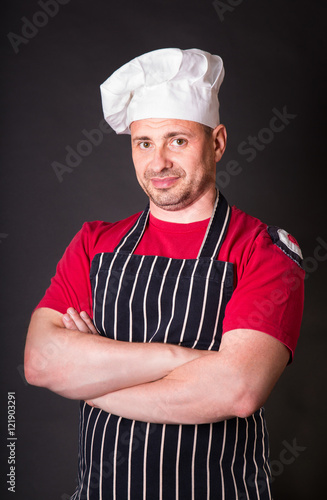 Handsome chef posing against black background
