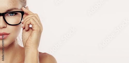 Closeup portrait of young beautiful woman face in spectacles over pink background with copy space. Concept of vision, eye care and medicine. 