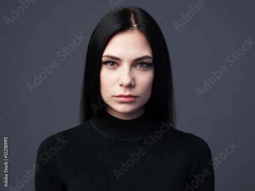 Beautiful serious woman with sad look, gray background