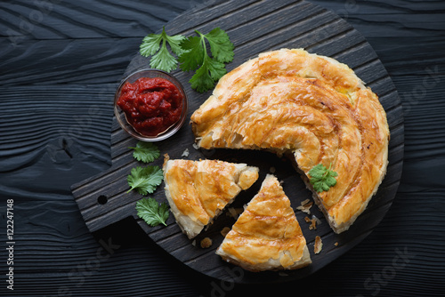 Burek pie with meat over black wooden background, above view