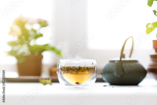 Teapot and glass cup with flower and herbal green tea