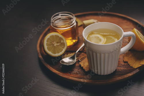 cooking ginger, lemon and honey hot tea in dark rustic interior. Ingredients and cup on wooden background