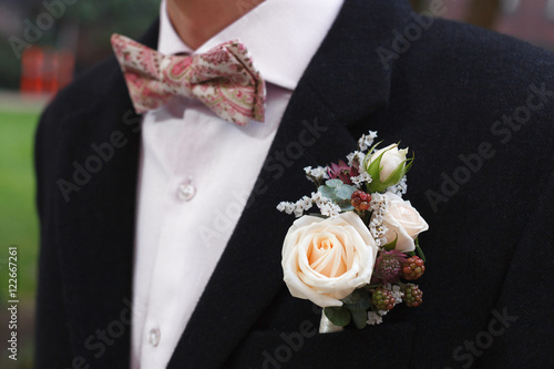 Ivory roses and blackberries boutonniere on black suit of the groom