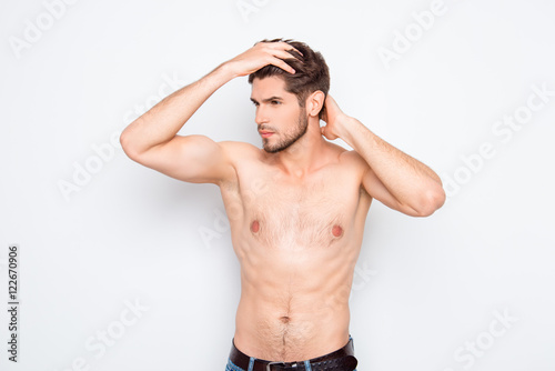 Healthy muscular young guy combing his hair