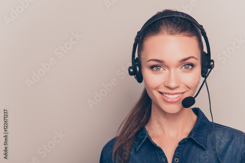Beautiful consultant of call center in headphones on gray backgr
