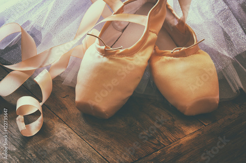 Image of silk pointe shoes and tutu on wooden floor. Vintage filtered